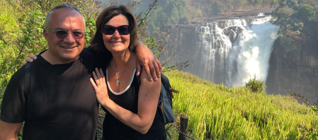 elderly couple standing in front a water fall