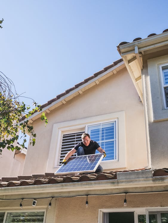 man in blue shirt and black pants sitting on roof