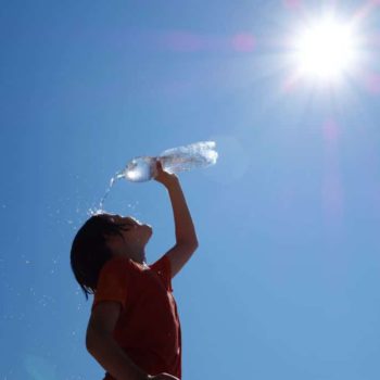 kid washing his face with a bottle of water during heatwave
