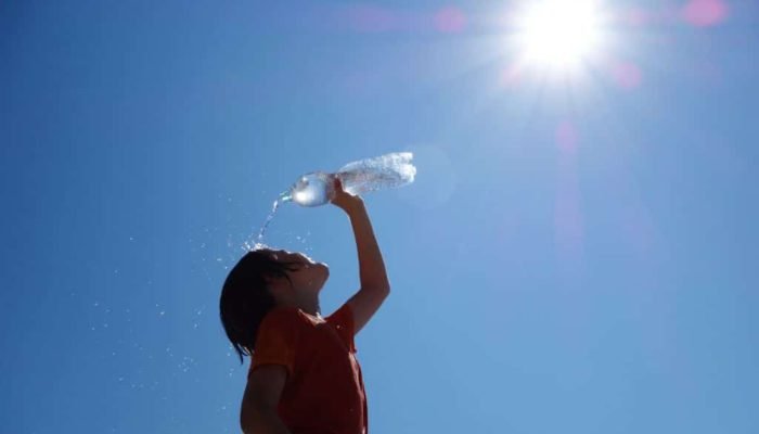 kid washing his face with a bottle of water during heatwave