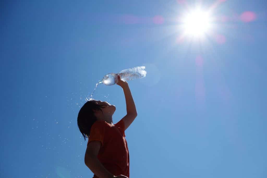 kid washing his face with a bottle of water during heatwave
