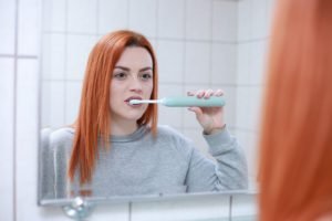 women brushing in front of mirror