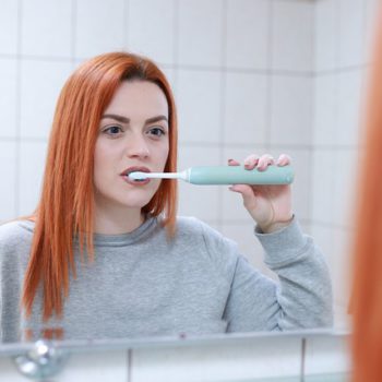 women brushing in front of mirror