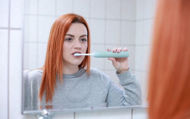 women brushing in front of mirror