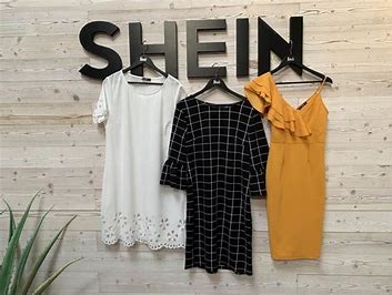 three dress hanging in hanger behind written SHEIN on wall