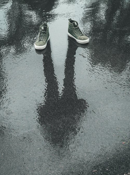 person wearing sneaker standing in a wet road