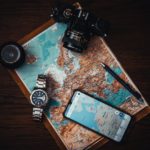 smartphone, watch, camera, compass over a world map