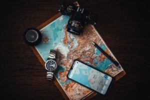 smartphone, watch, camera, compass over a world map