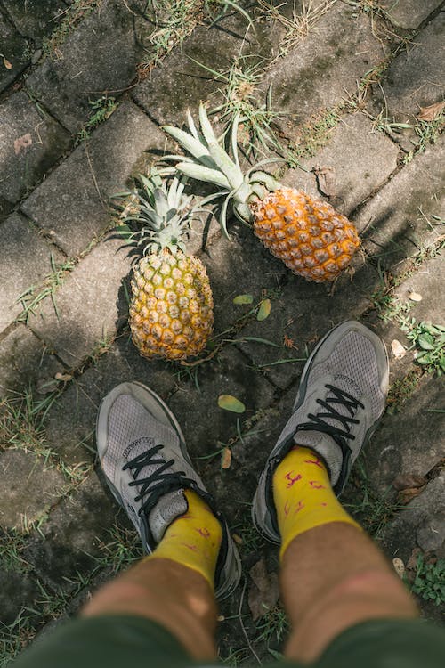 person wearing footwear beside pineapple