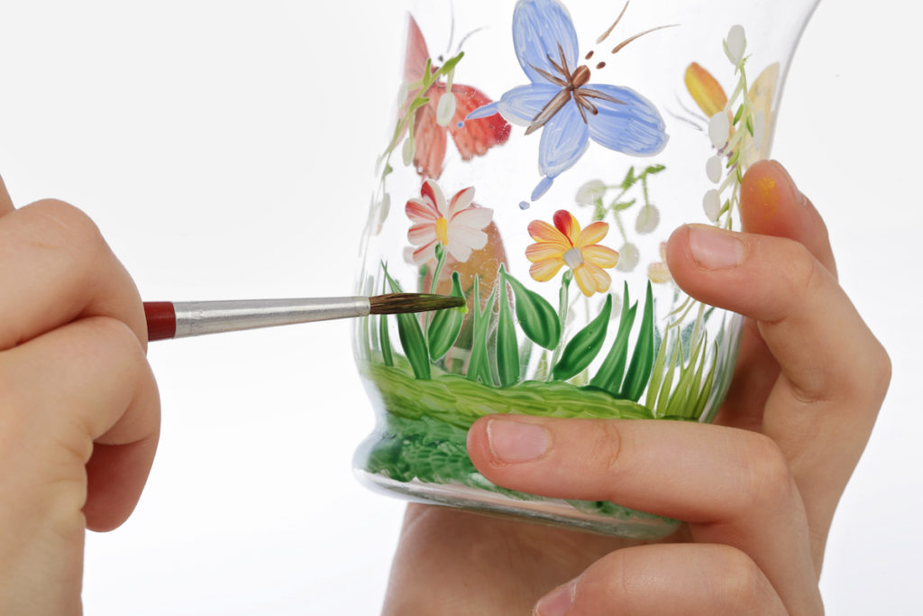 painting grass and butterflies on glass with a paintbrush