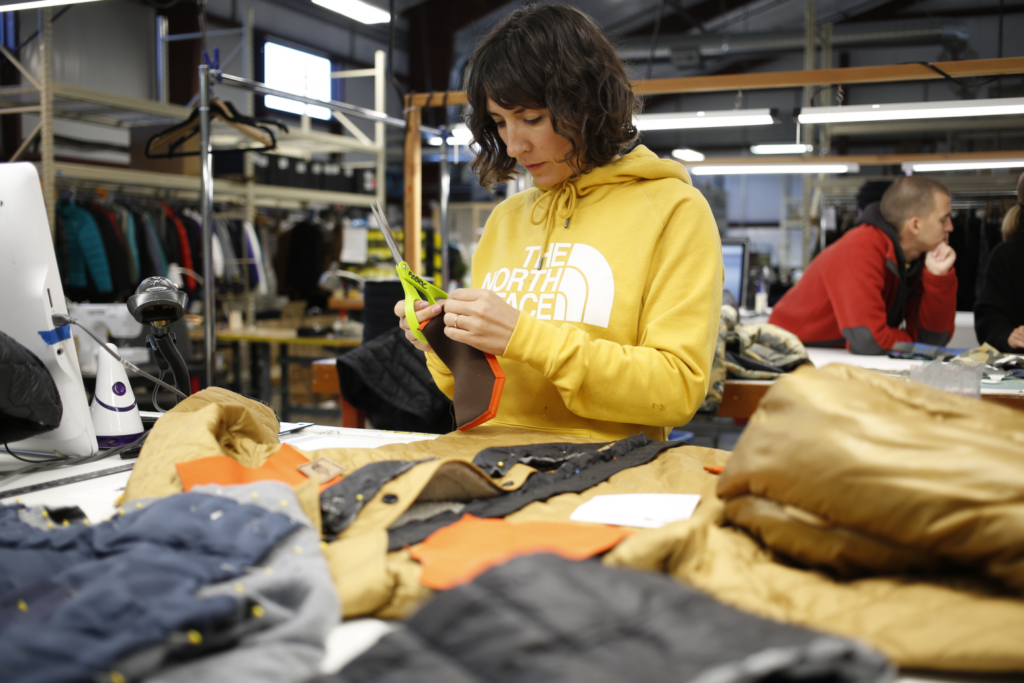 women working on garment product wearing yellow hoodie
