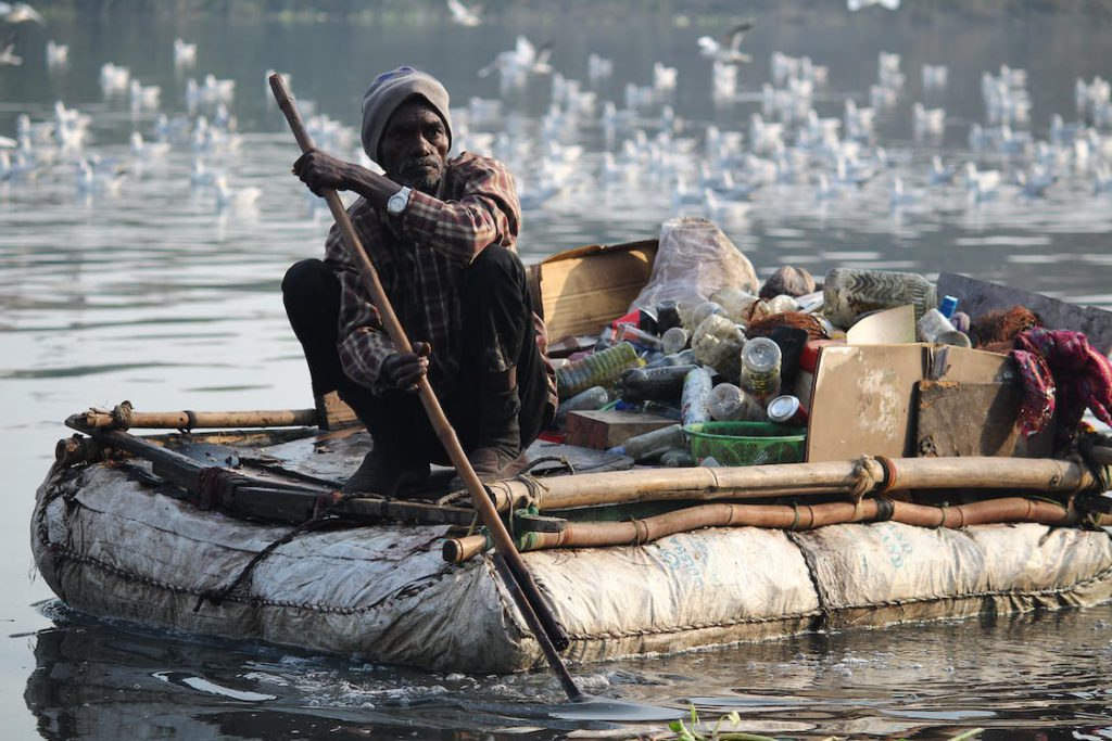 person using DIY boat to carry plastic in water route