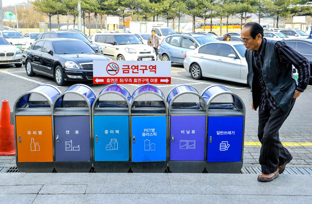 A man walks past separated dustbin for the recycling of waste materials at a rest stop of an expressway