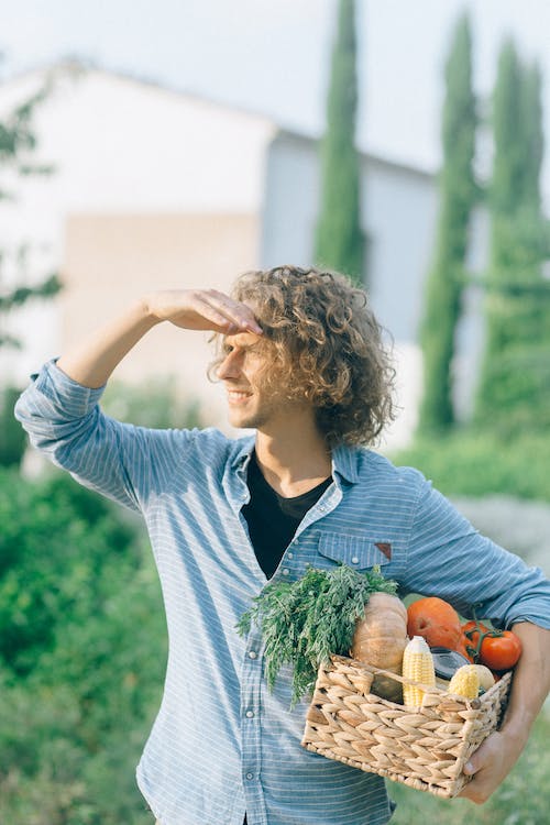a person looking far away holding vegetable basket with his hand