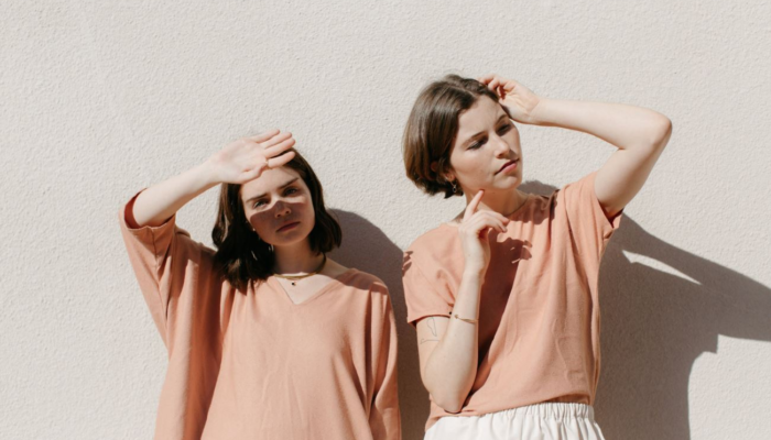 two women standing under sunlight wearing orange outfit