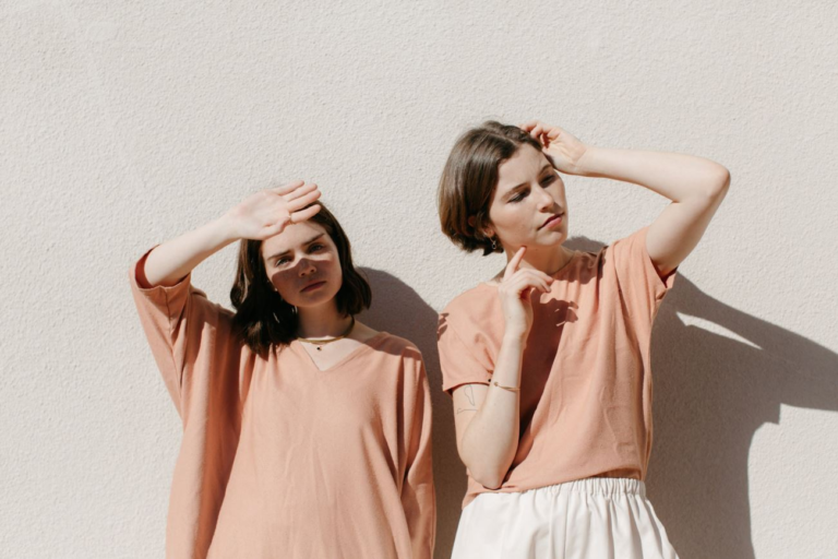 two women standing under sunlight wearing orange outfit