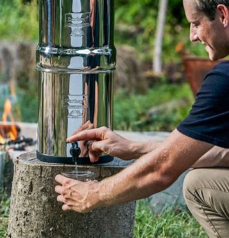 person pouring water in a onetime glass from Berkey water filter