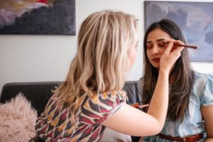 woman applying make up to another woman