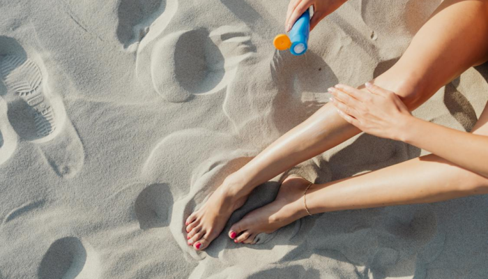 woman applying sunscreen on bare leg