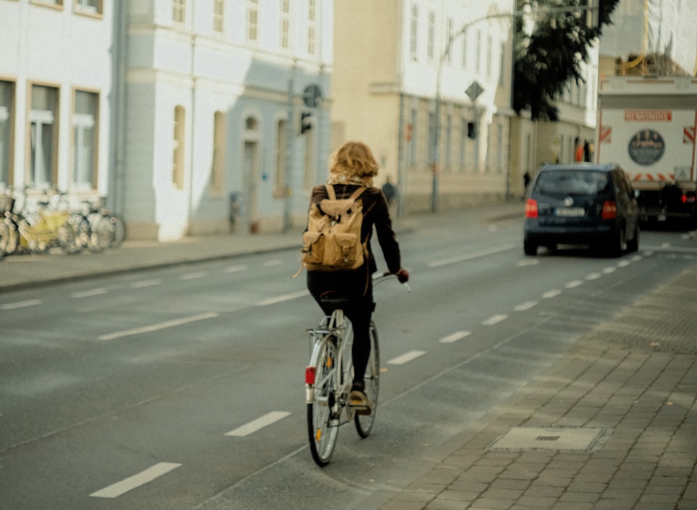 woman in black jacket riding bicycle on road during daytime 