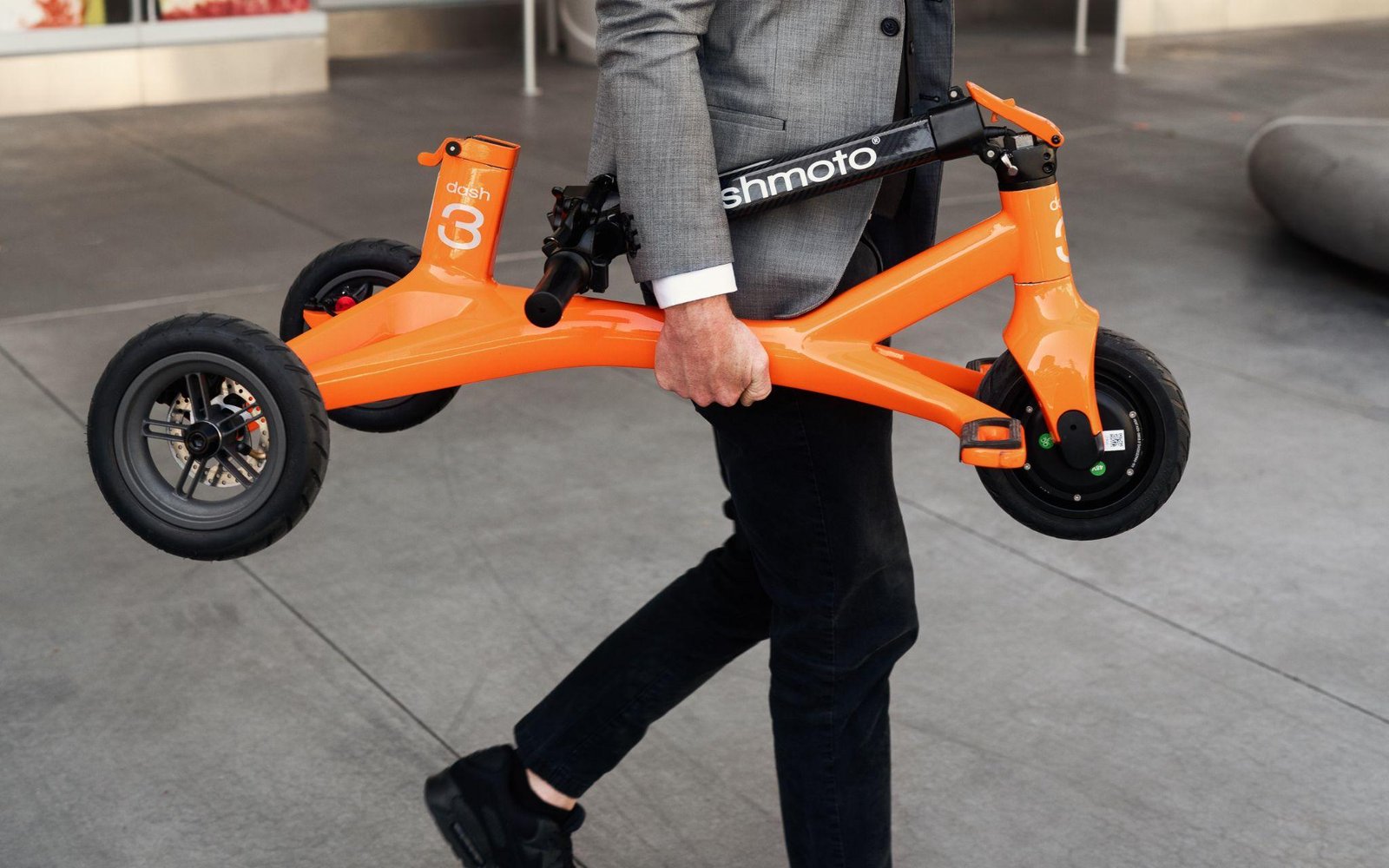 a person carrying an electric scooter in his hand