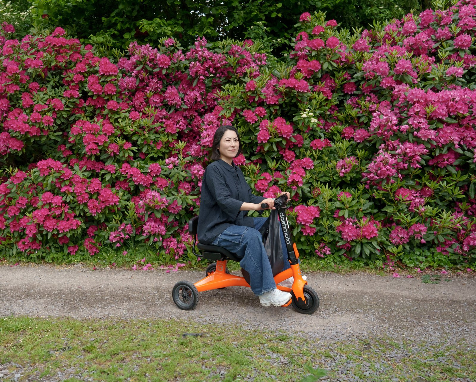 women on an electric scooter beside flower garden
