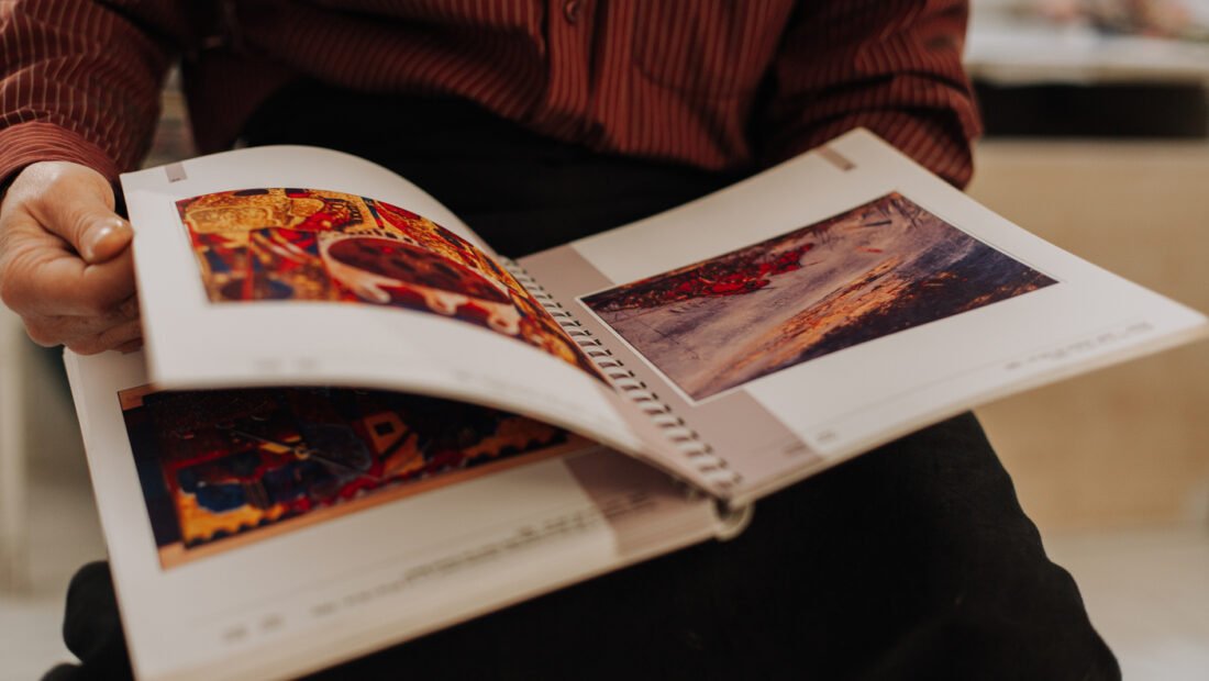 Healthy looking senior man is his late 70s sitting in garden at home and reading book, outdoor.