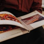 Healthy looking senior man is his late 70s sitting in garden at home and reading book, outdoor.